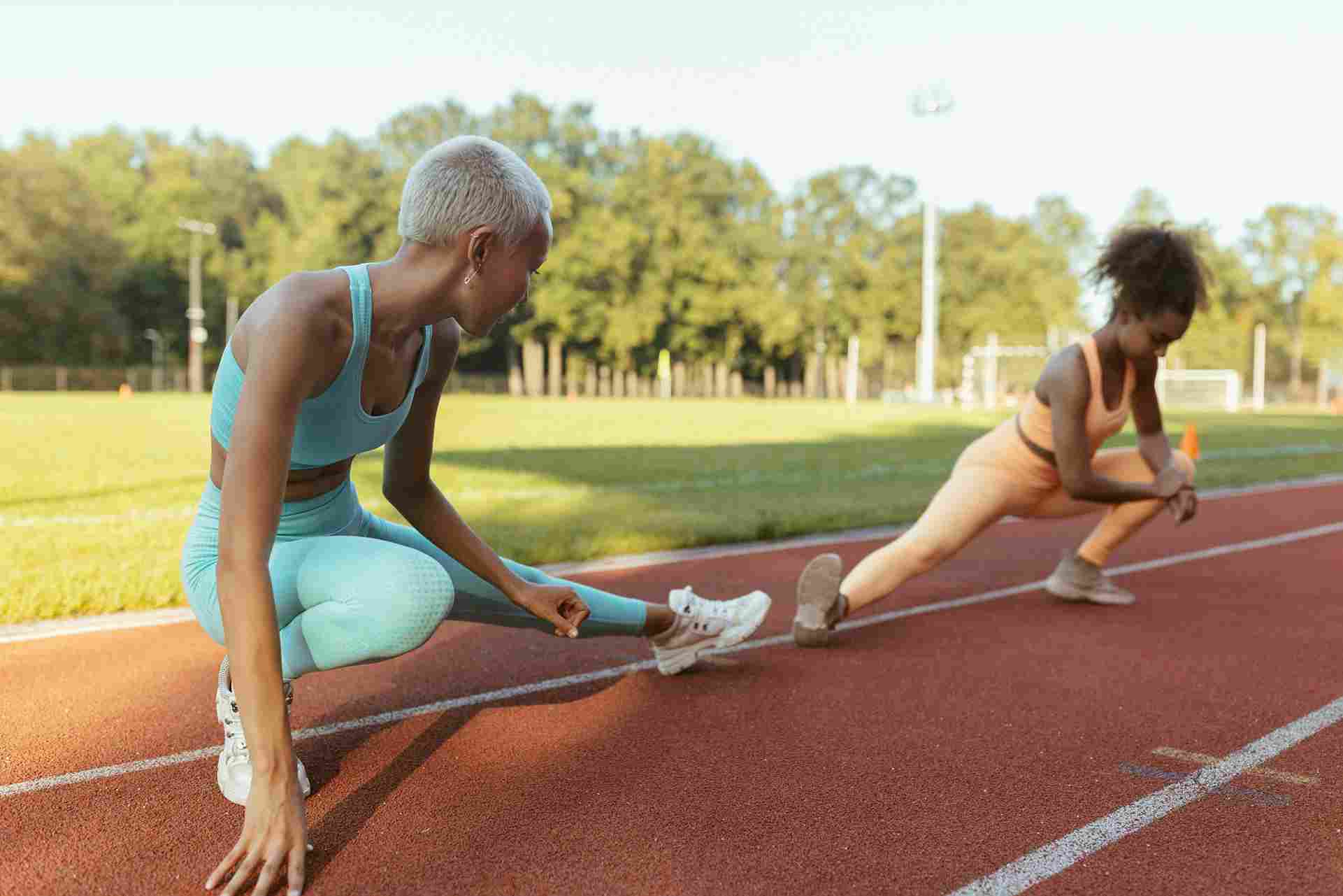 Two women stretching on an outdoor track